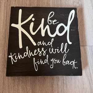 Small, black, decorative sign. “Be kind and kindness will follow you back.”